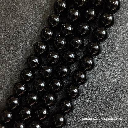 Close up of natural pure black obsidian crystal beads strands with deep jet black reflections