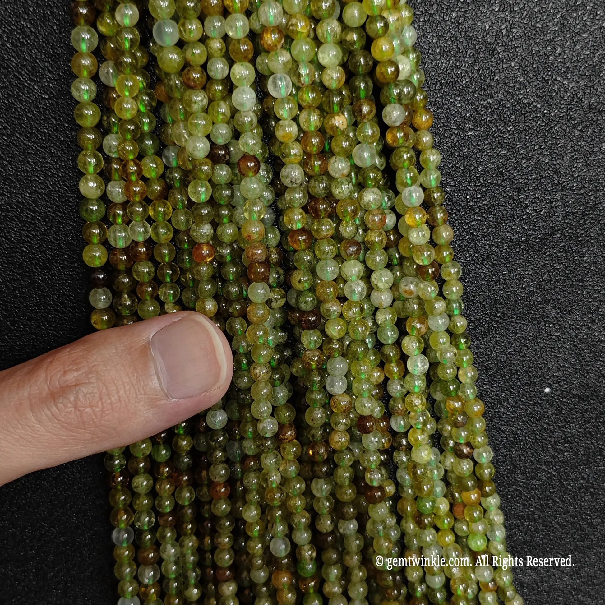 neatly arranged polished strands of natural semi translucent green garnet gemstone beads