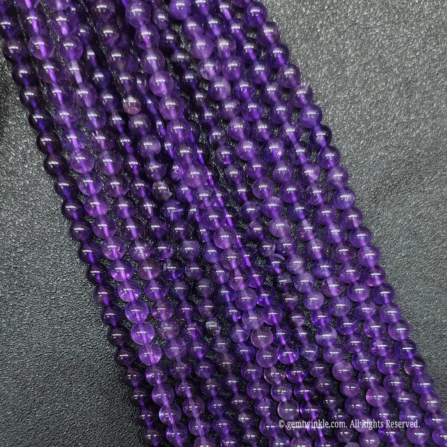 Multiple parallel rows of wholesale translucent violet amethyst round crystal beads for artisan jewelry making