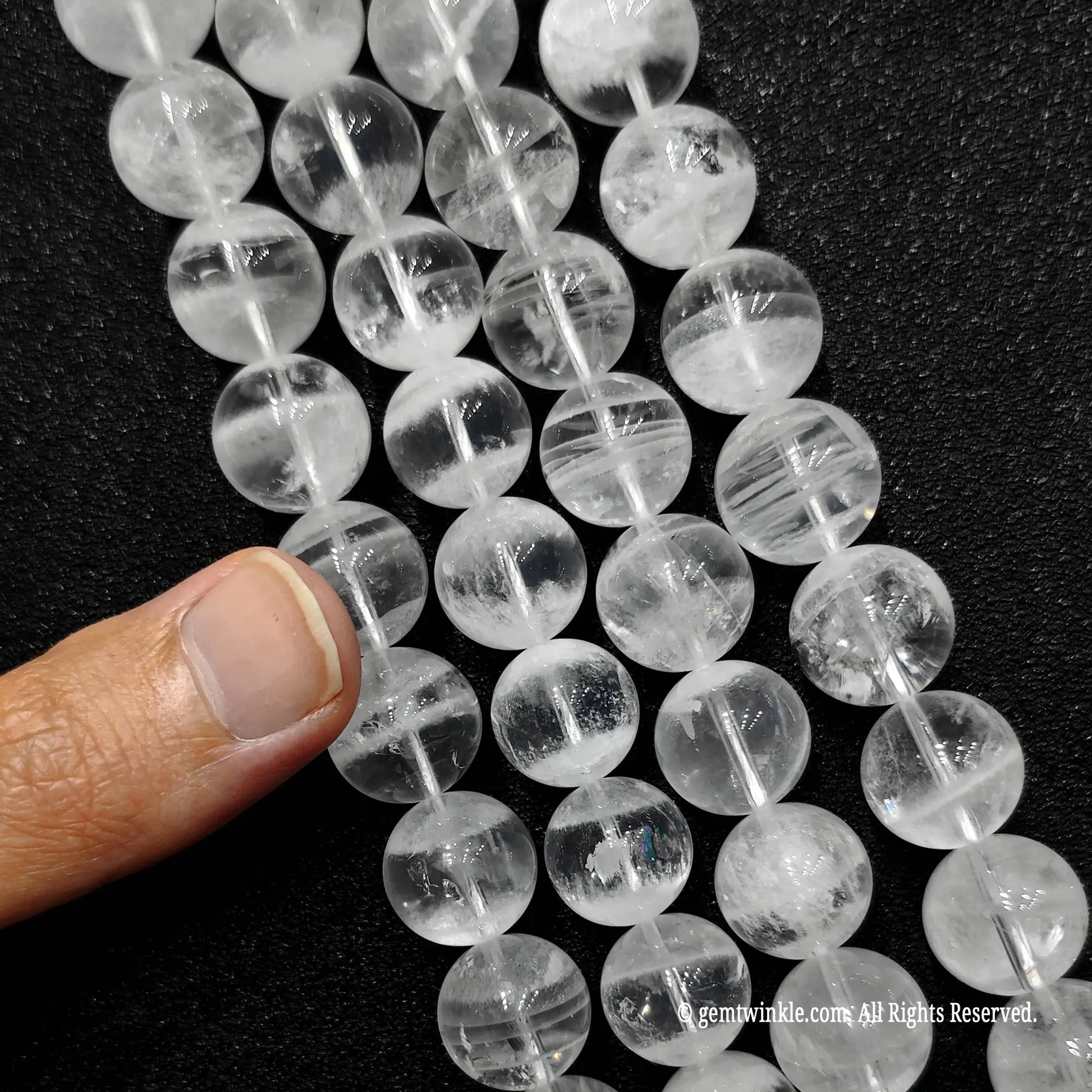 hand holding strands of natural white ghost quartz crystal beads to show sizes