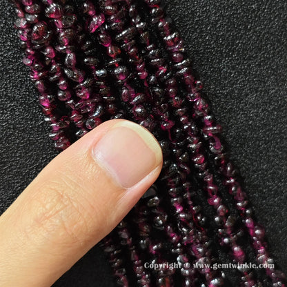 Close up view of natural wine red garnet chip beads on hand showing strand yield