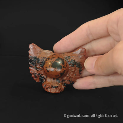 Side view of red obsidian winged skull carving