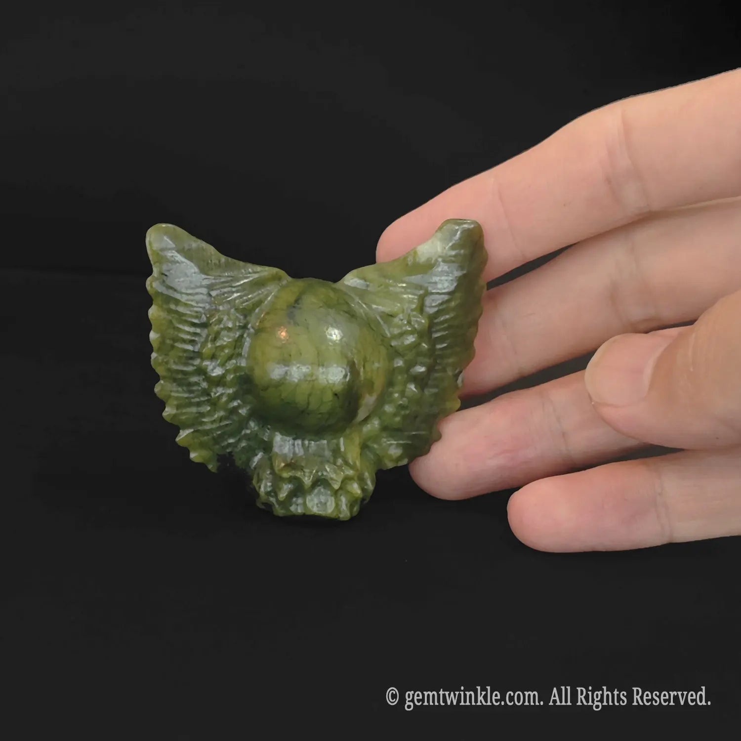 Side profile of serpentine stone winged skull figurine held in hand