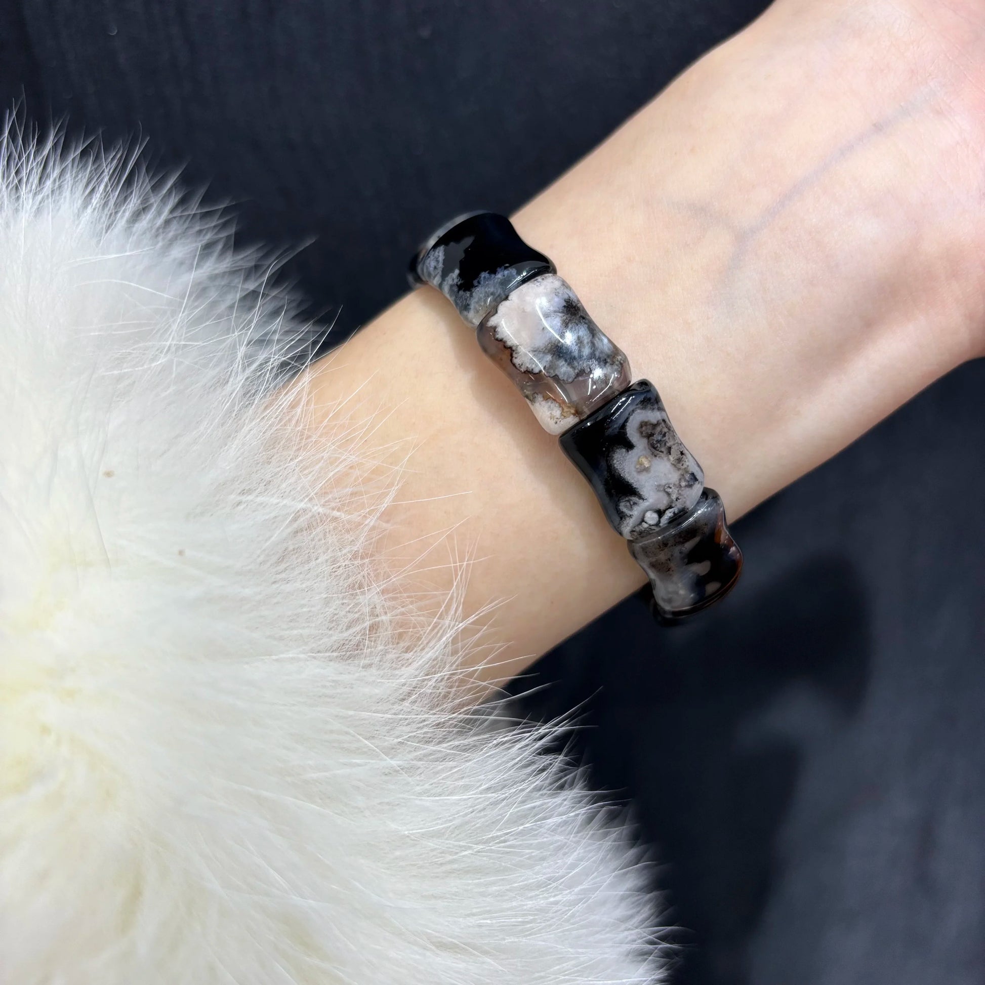 Woman wearing a natural black sakura agate bamboo bracelet on wrist.