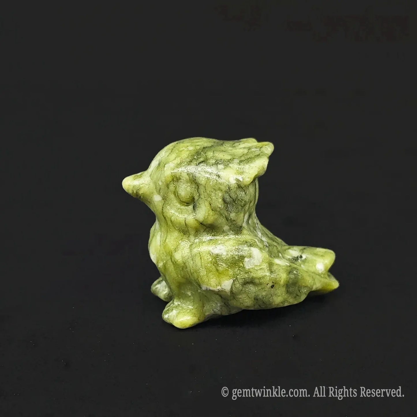 Side angle of a woodland serpentine stone chubby owl carving displaying natural mossy olive green and yellow mineral patterns