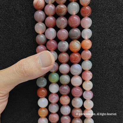 Inspecting a bulk bunch of yanyuan agate round beads from 6mm to 14mm with finger for store size grid verification