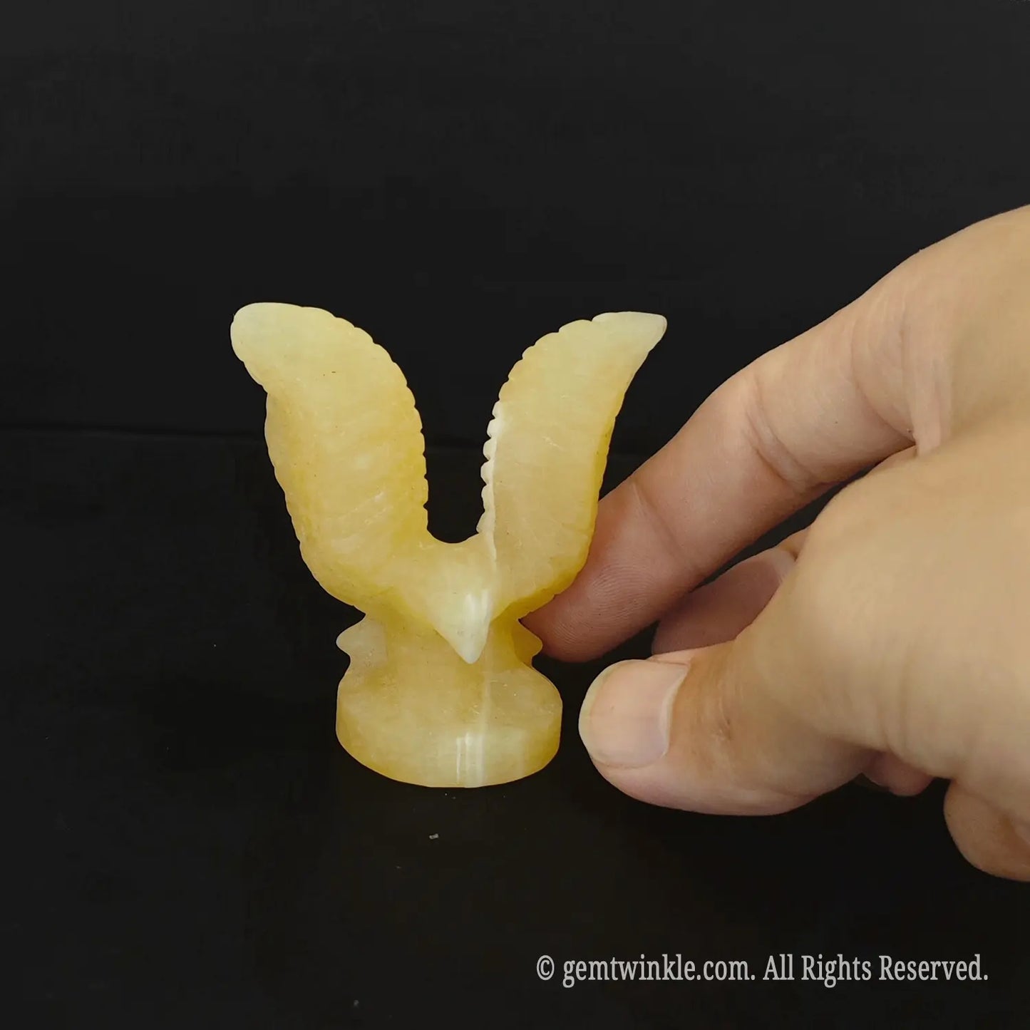 Front look of carved yellow calcite eagle totem showing polished translucent mineral luster