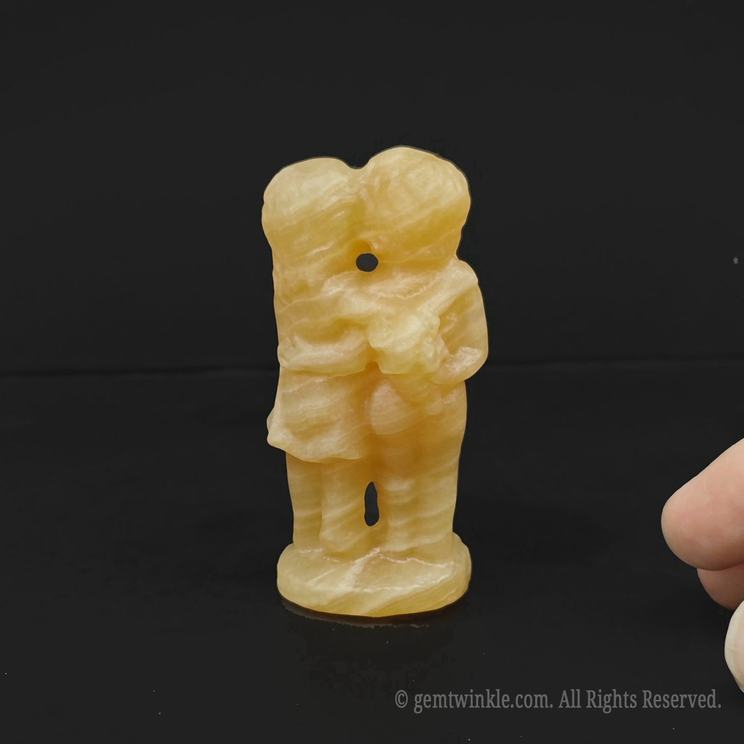 Yellow stone carving of a figure on a black background