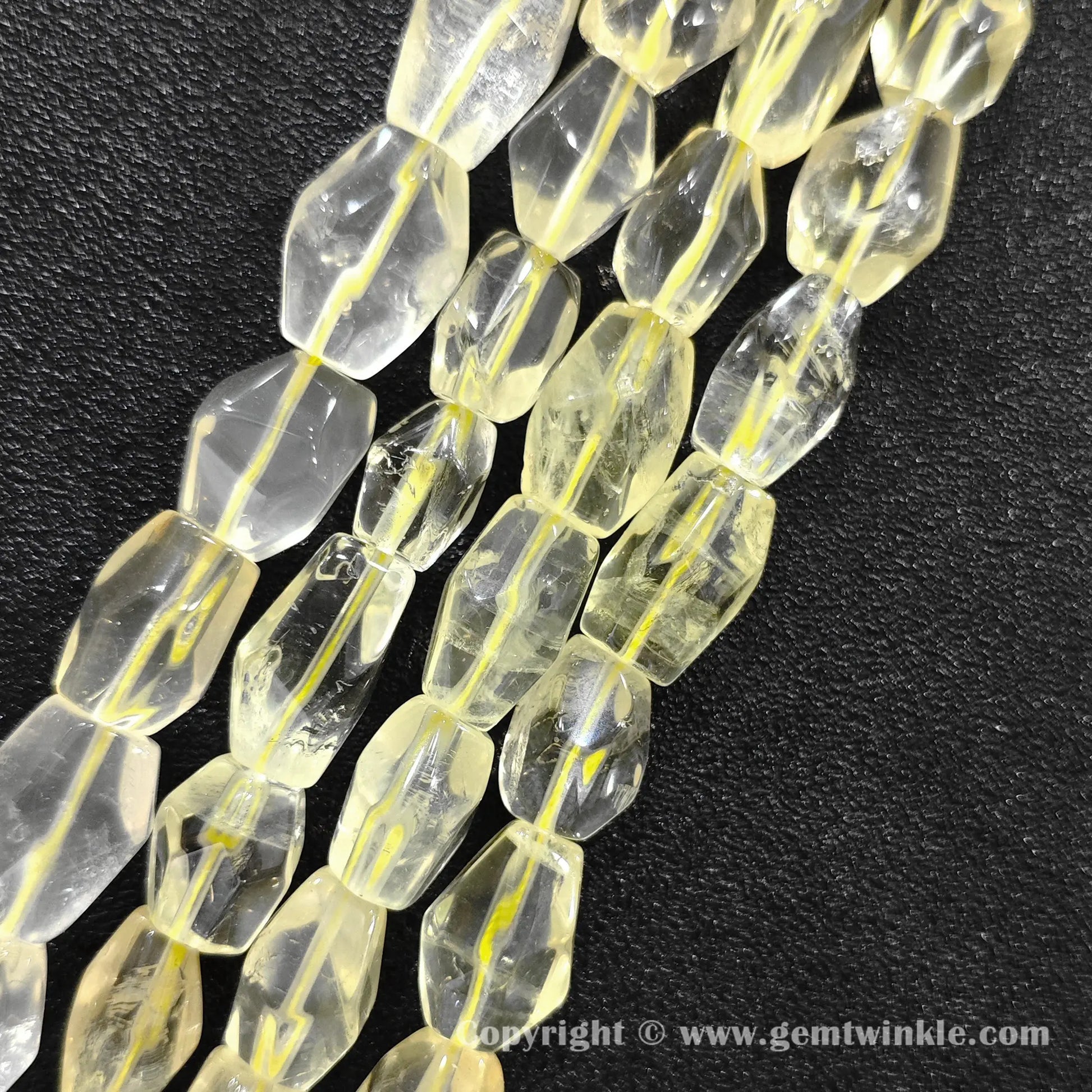 Close up view of yellow lemon quartz polygonal column cut beads on dark surface