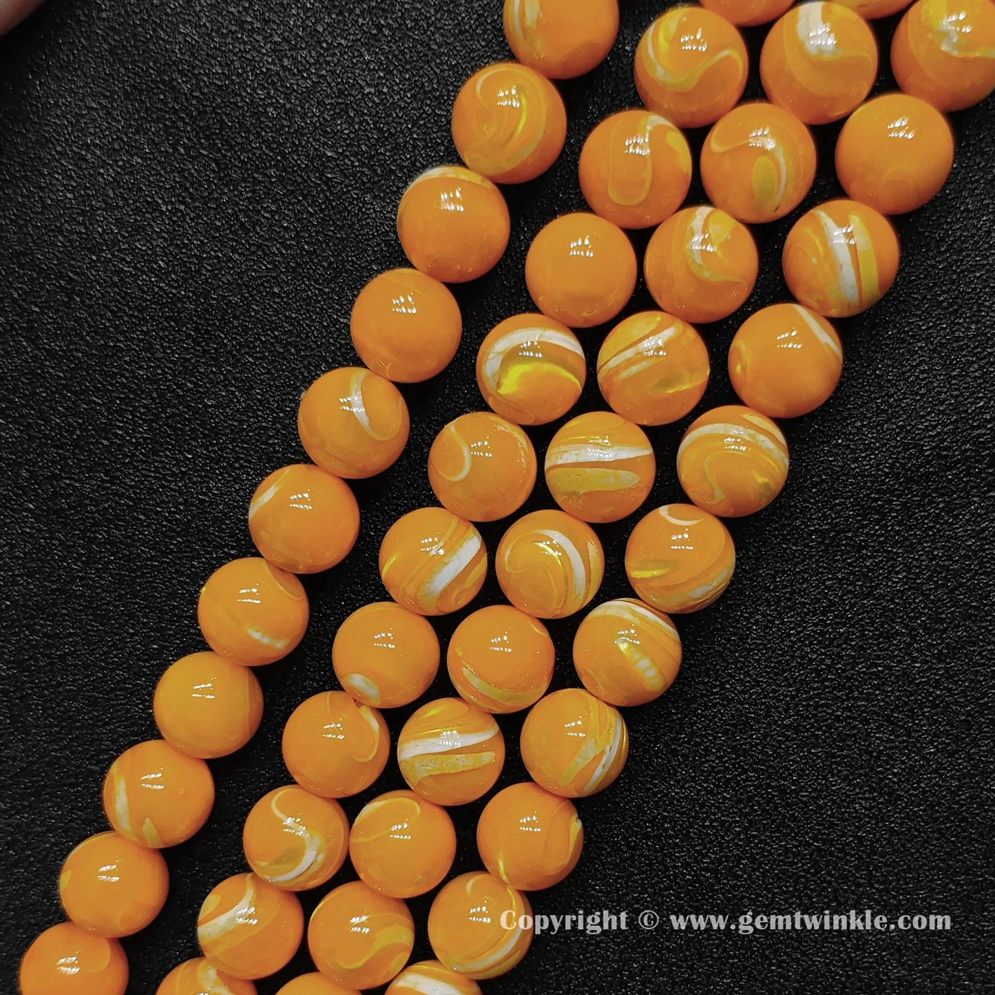 Multiple strands of bright dyed yellow shell round beads lined up on dark surface