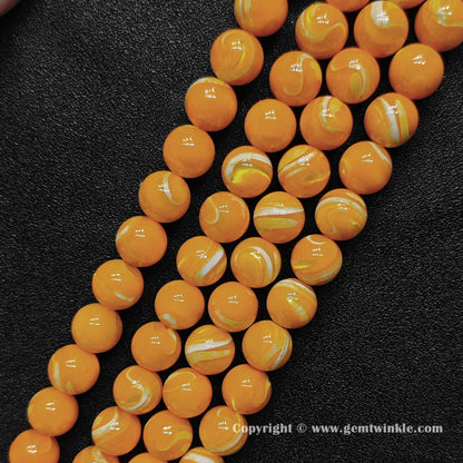 Multiple strands of bright dyed yellow shell round beads lined up on dark surface