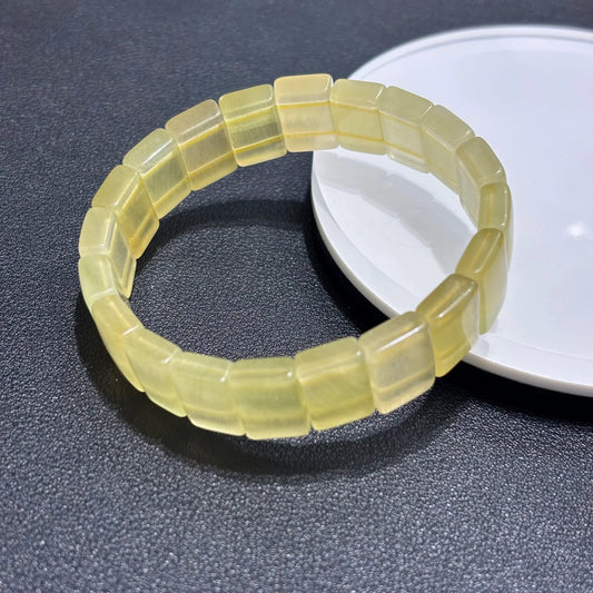 Natural Yellow Fluorite Bangle Bracelet displayed on a white plate, emphasizing the square bead shape and smooth finish.