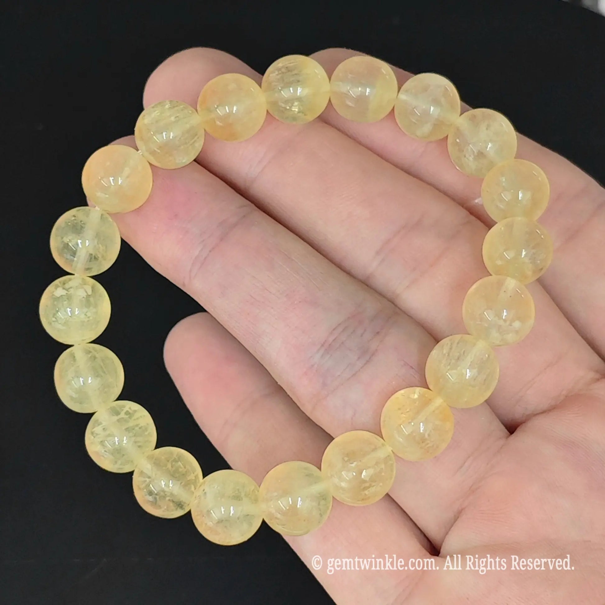 golden yellow fluorite round bead strand laid flat across fingers