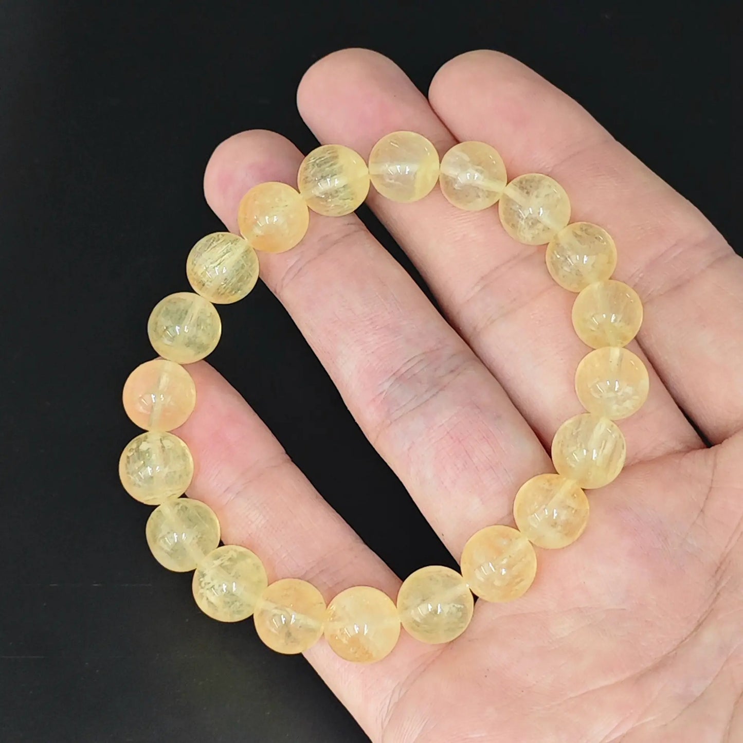 hand holding yellow fluorite round beads stretch bracelet