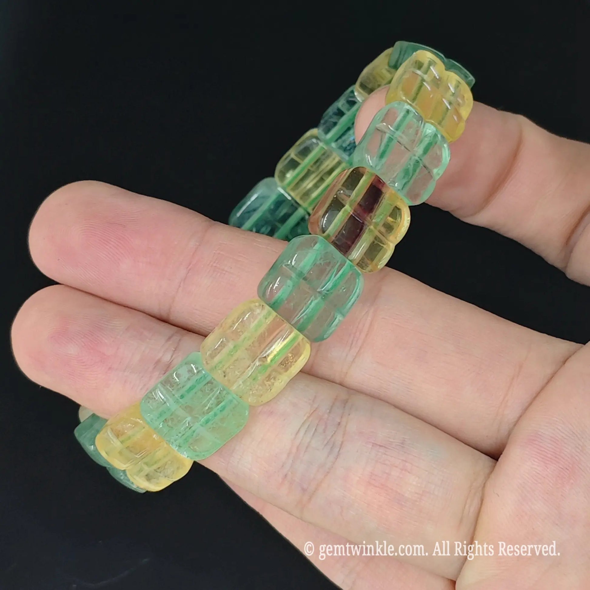 hand holding translucent green and yellow fluorite grid pattern segment stretch bracelet