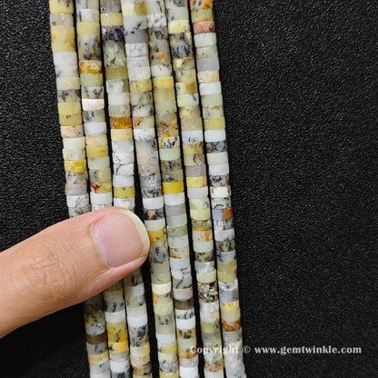 Close up view of 6x3mm yellow opal disc rondelle beads inspected on fingers for quality preview