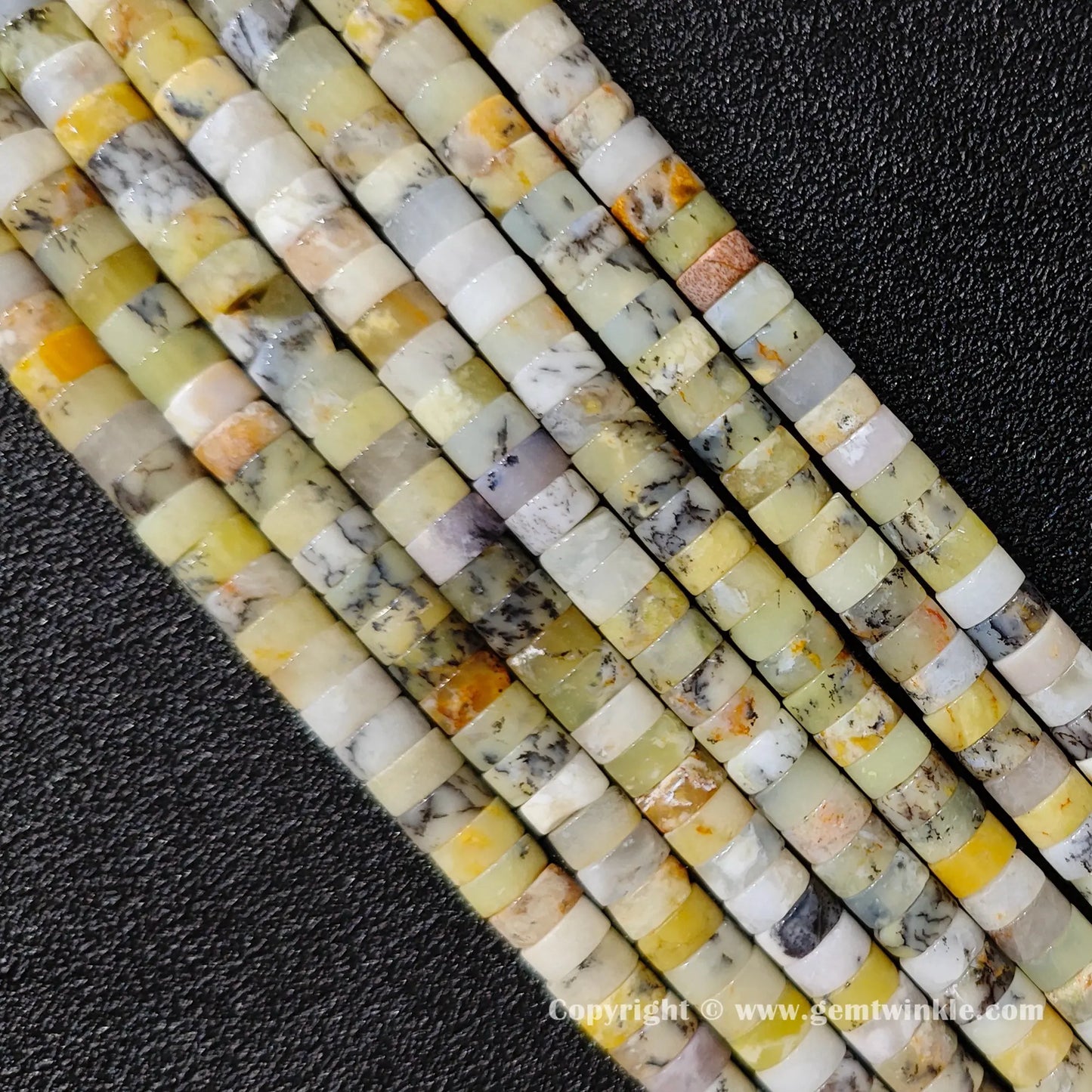Angled view of natural yellow opal flat disc gemstone strands arranged parallel on dark background