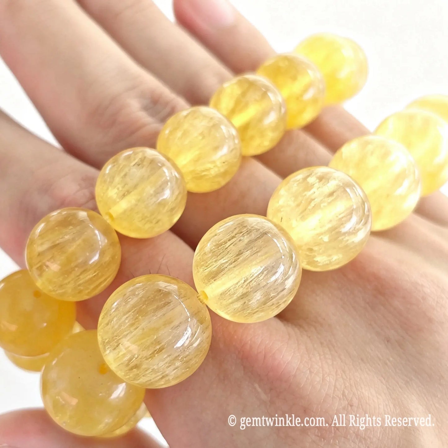 High transparency yellow silk fluorite bead bracelet resting on fingers displaying vibrant golden warmth and inner fiber lines