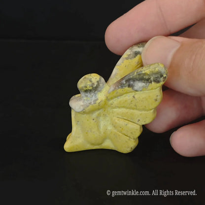 Side look of carved matte yellow stone flower fairy figurine showing large butterfly wing details