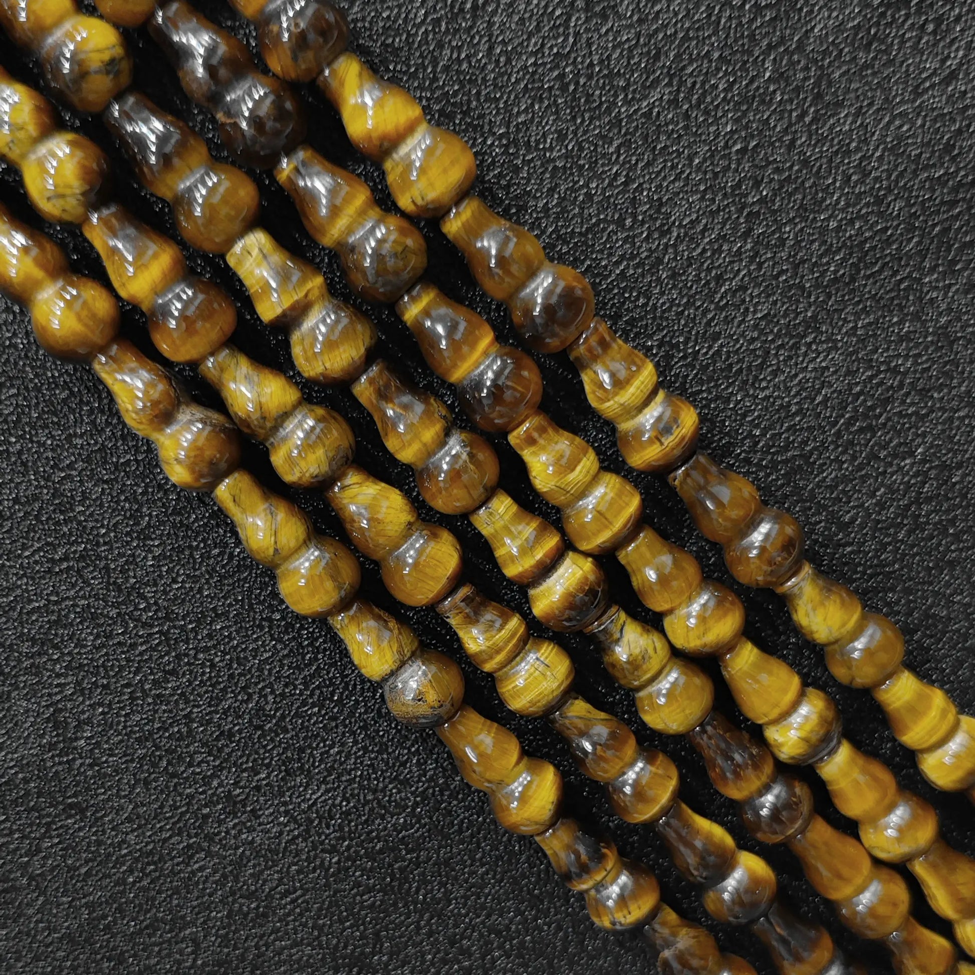 Macro closeup of natural yellow tiger eye gourd beads showing golden chatoyancy sheen