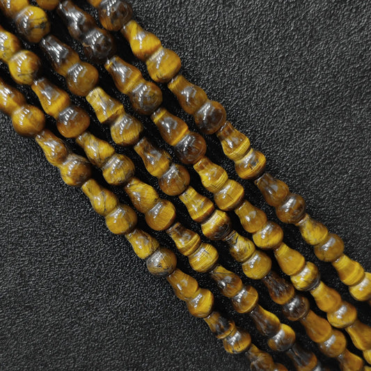 Macro closeup of natural yellow tiger eye gourd beads showing golden chatoyancy sheen