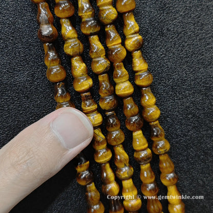 Natural yellow tiger eye gourd bead strand held over hand showing size scale