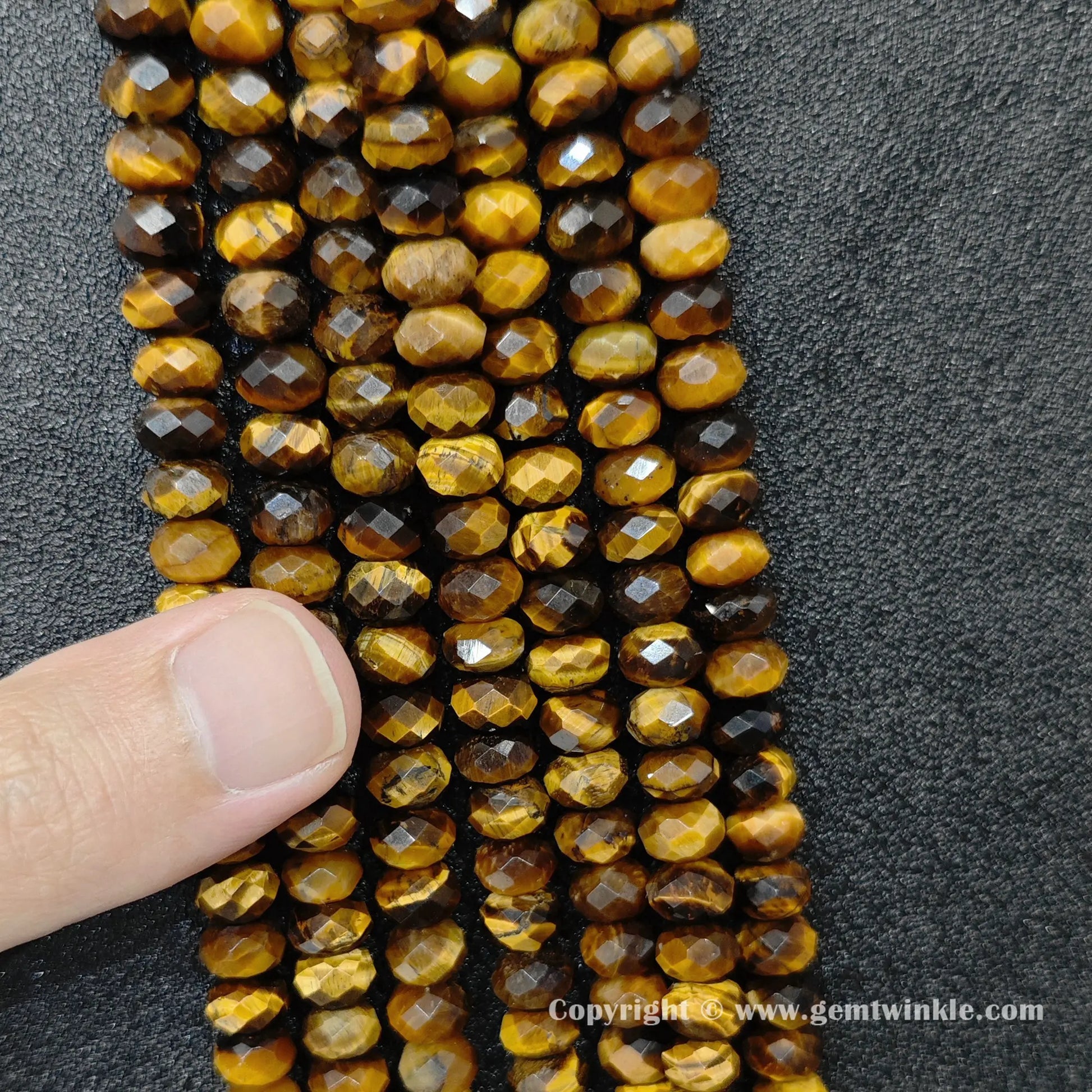 Close up view of yellow tiger eye rondelle beads inspected on hand for live size and luster preview