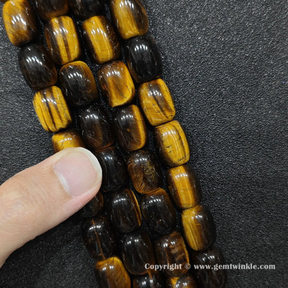 Natural yellow tigers eye barrel bead strand held over hand for size scale