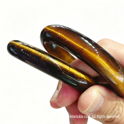 Angled view of two yellow tiger eye gemstone bangles showing classic circular contour and brilliant optical sheen