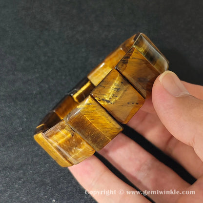 close up of yellow tigers eye plate cuff bracelet displaying natural silky texture and elastic cord