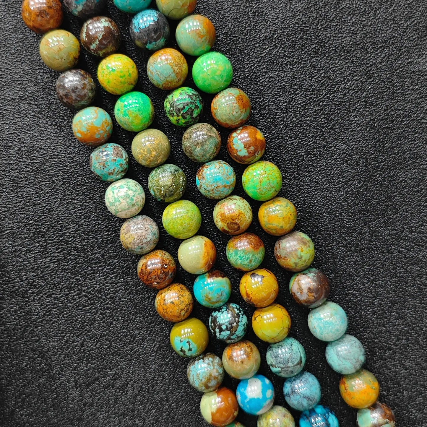 Macro closeup of yellowish chrysocolla phoenix stone smooth round beads showing golden green matrix