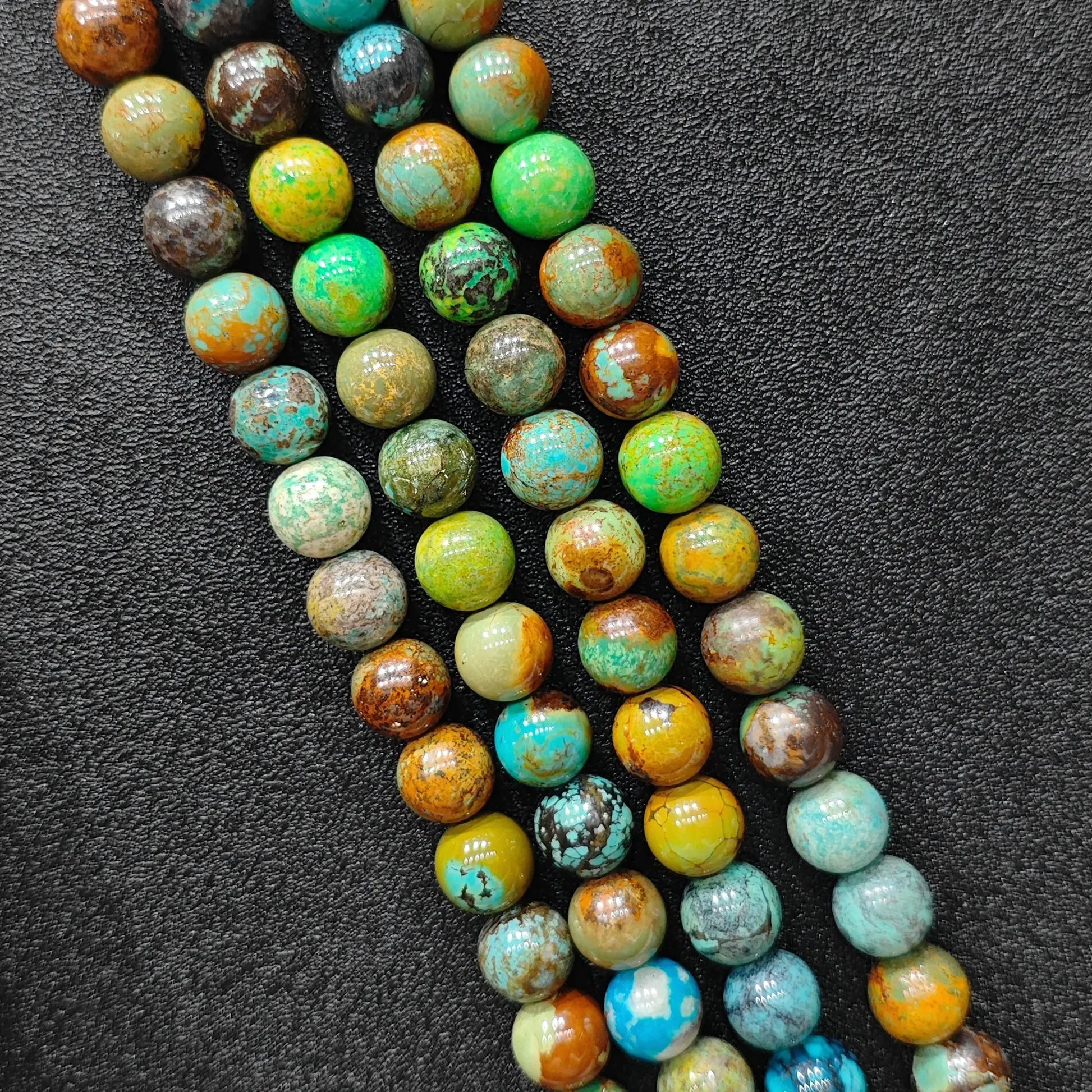 Macro closeup of yellowish chrysocolla phoenix stone smooth round beads showing golden green matrix