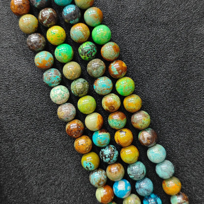 Macro closeup of yellowish chrysocolla phoenix stone smooth round beads showing golden green matrix