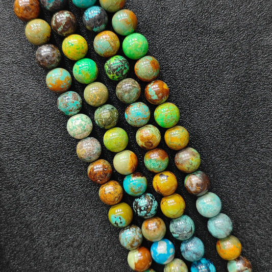 Macro closeup of yellowish chrysocolla phoenix stone smooth round beads showing golden green matrix