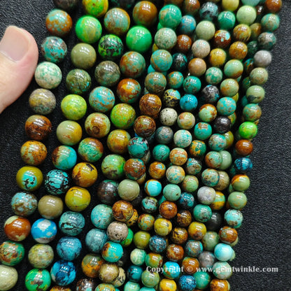 Close up view of yellowish phoenix stone round beads held on fingers for natural pattern preview