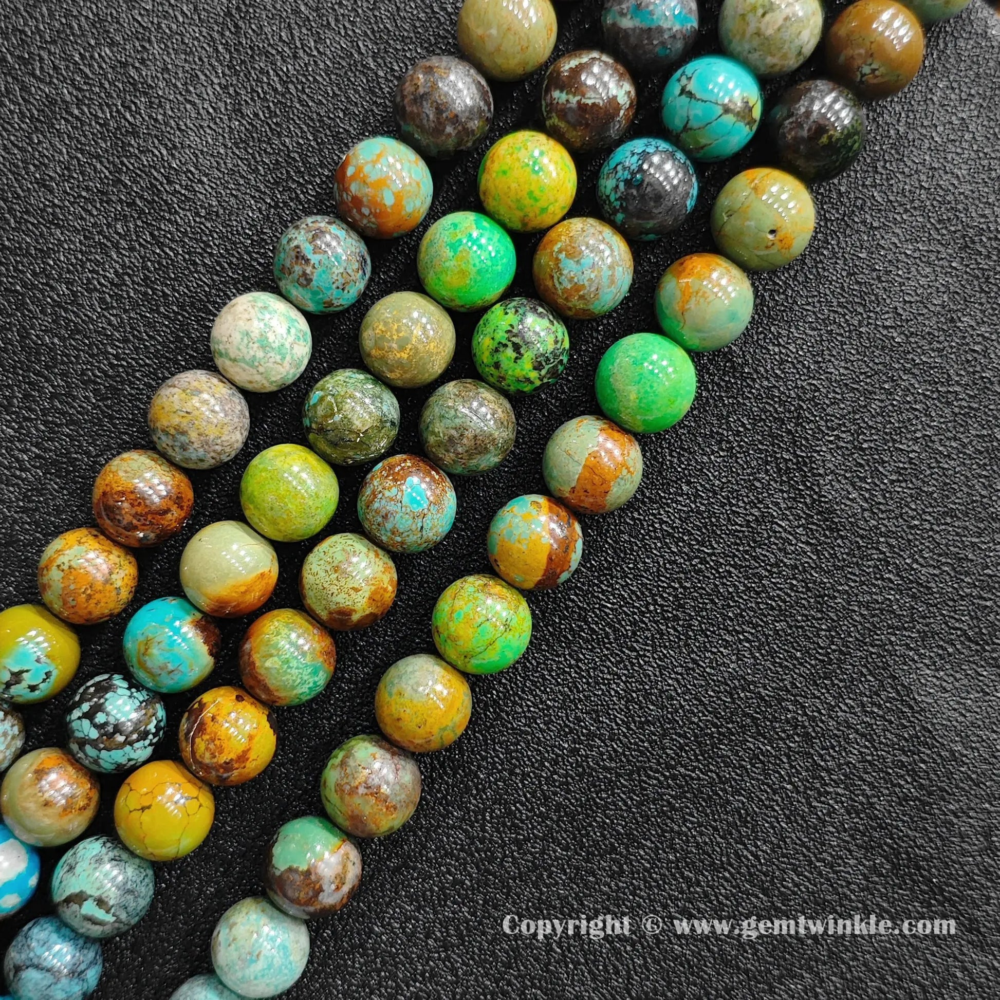 Angled view of yellowish phoenix stone round bead strands arranged parallel on dark textured backdrop